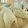 A close-up of a light green velvet bedding set featuring a duvet cover and pillows.