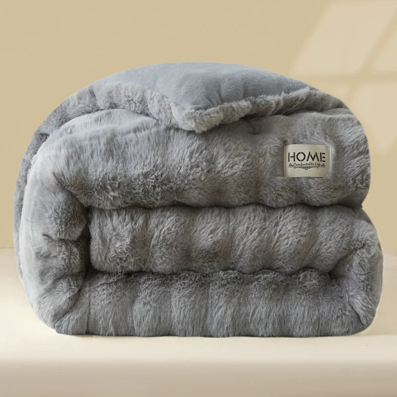 A thick, gray plush winter comforter or quilt folded neatly on a light surface.