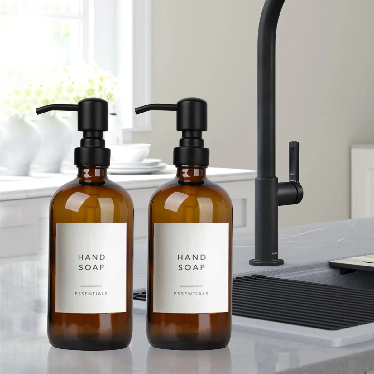 A set of amber glass hand soap dispensers with black stainless steel pumps sitting on a gray countertop.