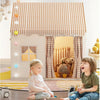 Two young children play in a princess castle play tent decorated with a checkered roof and fabric curtains.