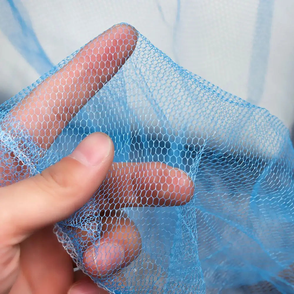 A hand holds a piece of light blue elegant lace canopy mosquito net fabric.