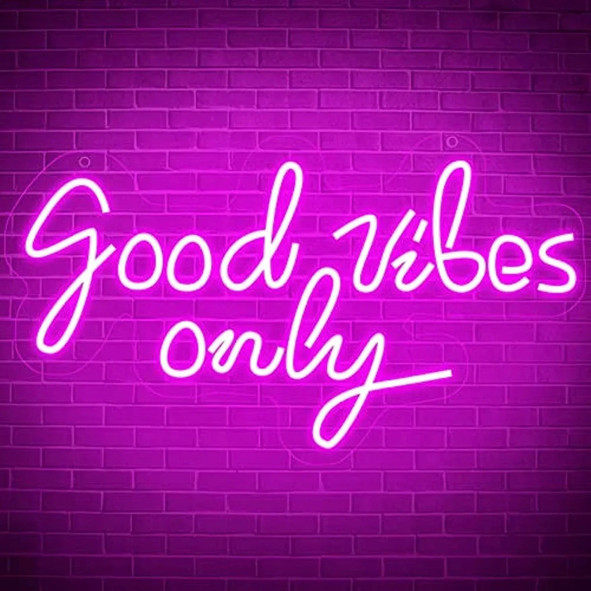 A neon sign glowing bright pink on a brick wall displaying the text Good vibes only