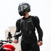 A person wearing a black CE-certified motocross armor jacket with chest and back protection standing next to a red motorcycle