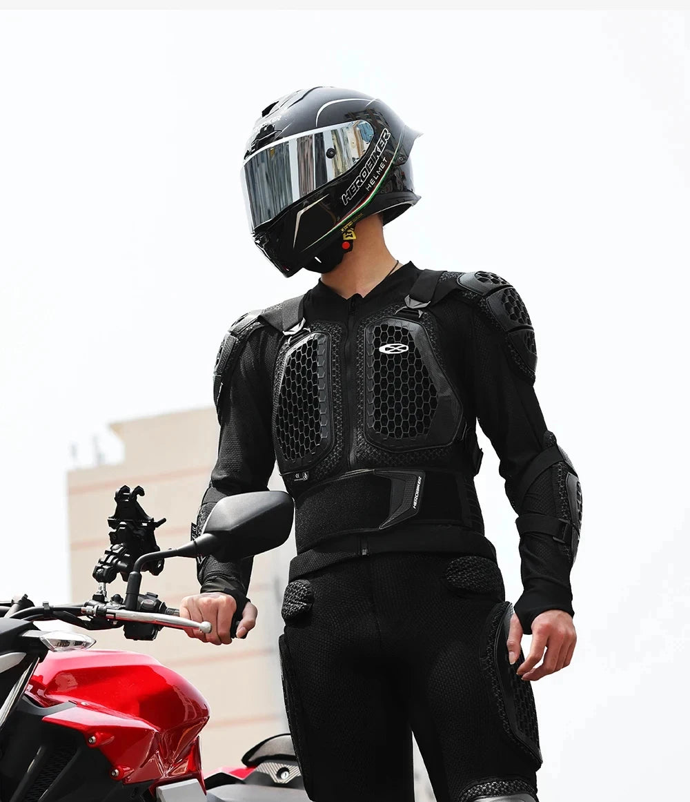A person wearing a black CE-certified motocross armor jacket with chest and back protection standing next to a red motorcycle