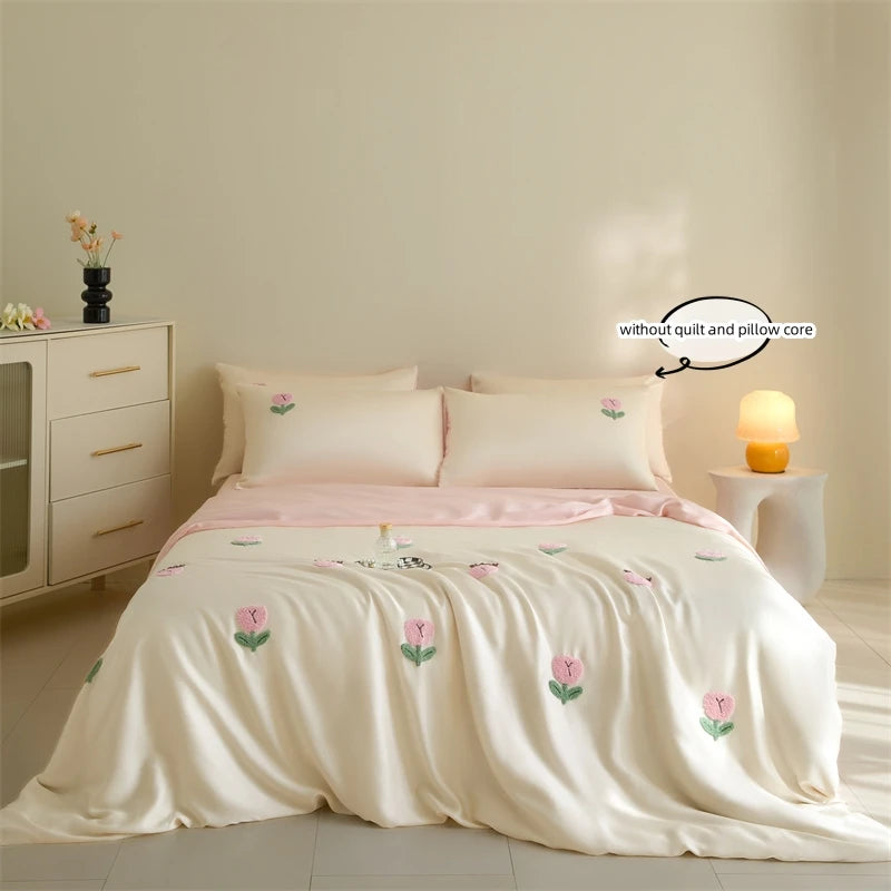 A light pink embroidered tulip duvet cover set displayed on a bed with white linens and a bedside table.