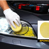 A gloved hand is cleaning a car headlight with a yellow sponge to restore clarity.