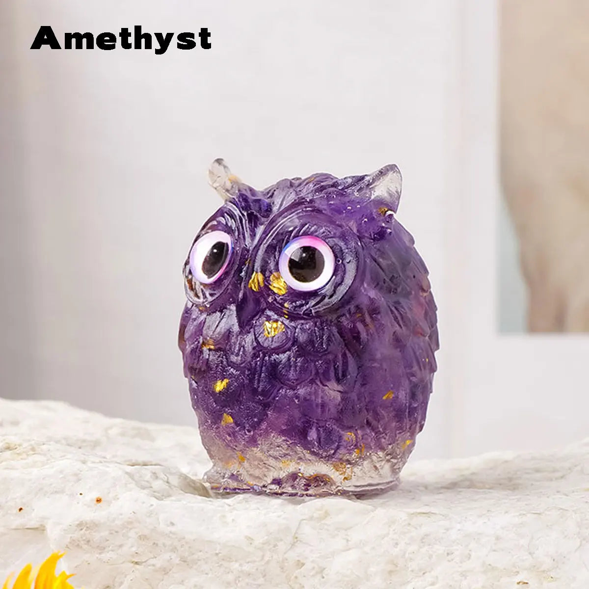 A handcrafted amethyst crystal owl figurine with a natural crushed stone finish sitting on a white surface.