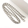 Silver metal chain purse strap with a secure buckle lying on a white surface.