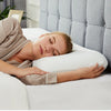 A woman is sleeping comfortably on a white memory foam pillow in a modern bedroom setting.