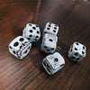 A set of white skull dice with black spots resting on a dark wooden surface.