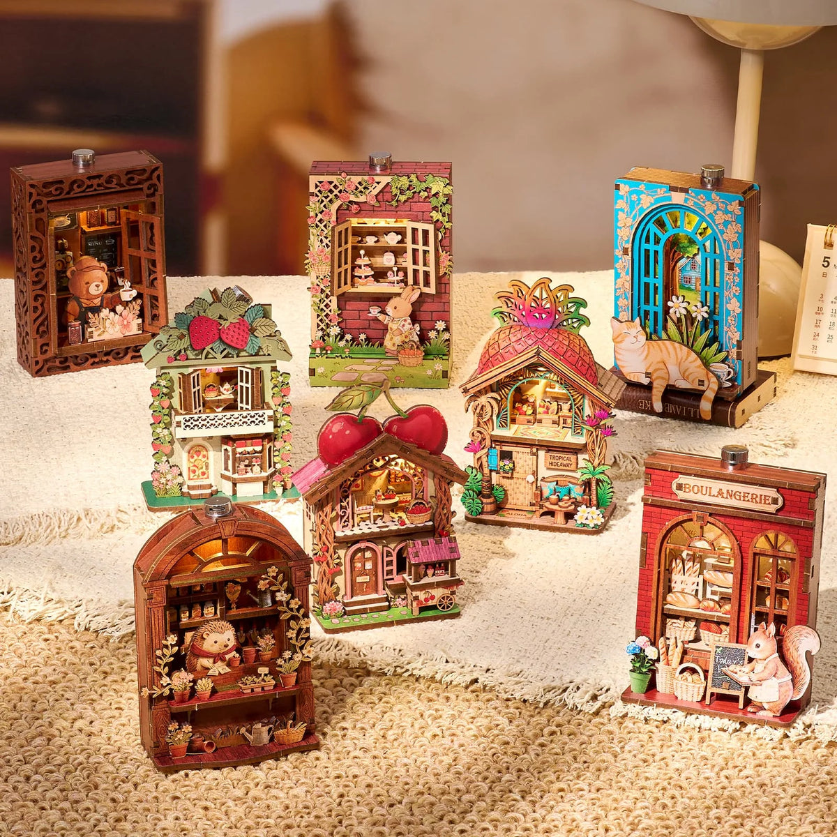 A collection of DIY book nook fridge magnets featuring miniature wooden houses and scenes with LED lighting.