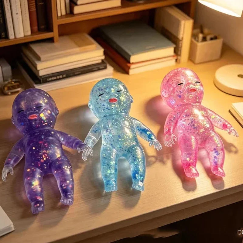 Three squishy stress relief toys in purple, blue, and pink with a shimmer finish displayed on a wooden shelf.