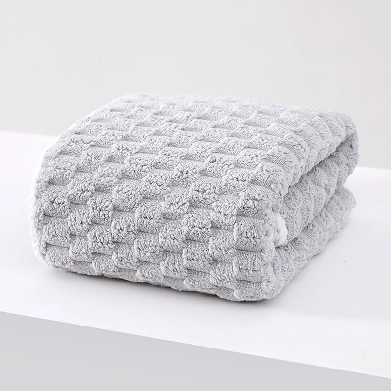A thick, gray, textured plush bath towel folded neatly on a white surface.
