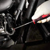 A hand uses a metal pick to remove a seal or O-ring from an automotive component.