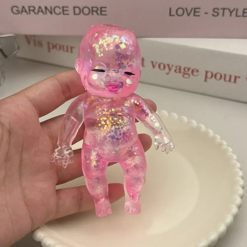 A small, translucent pink squishy stress relief toy with a shimmering finish is held above a white dish.