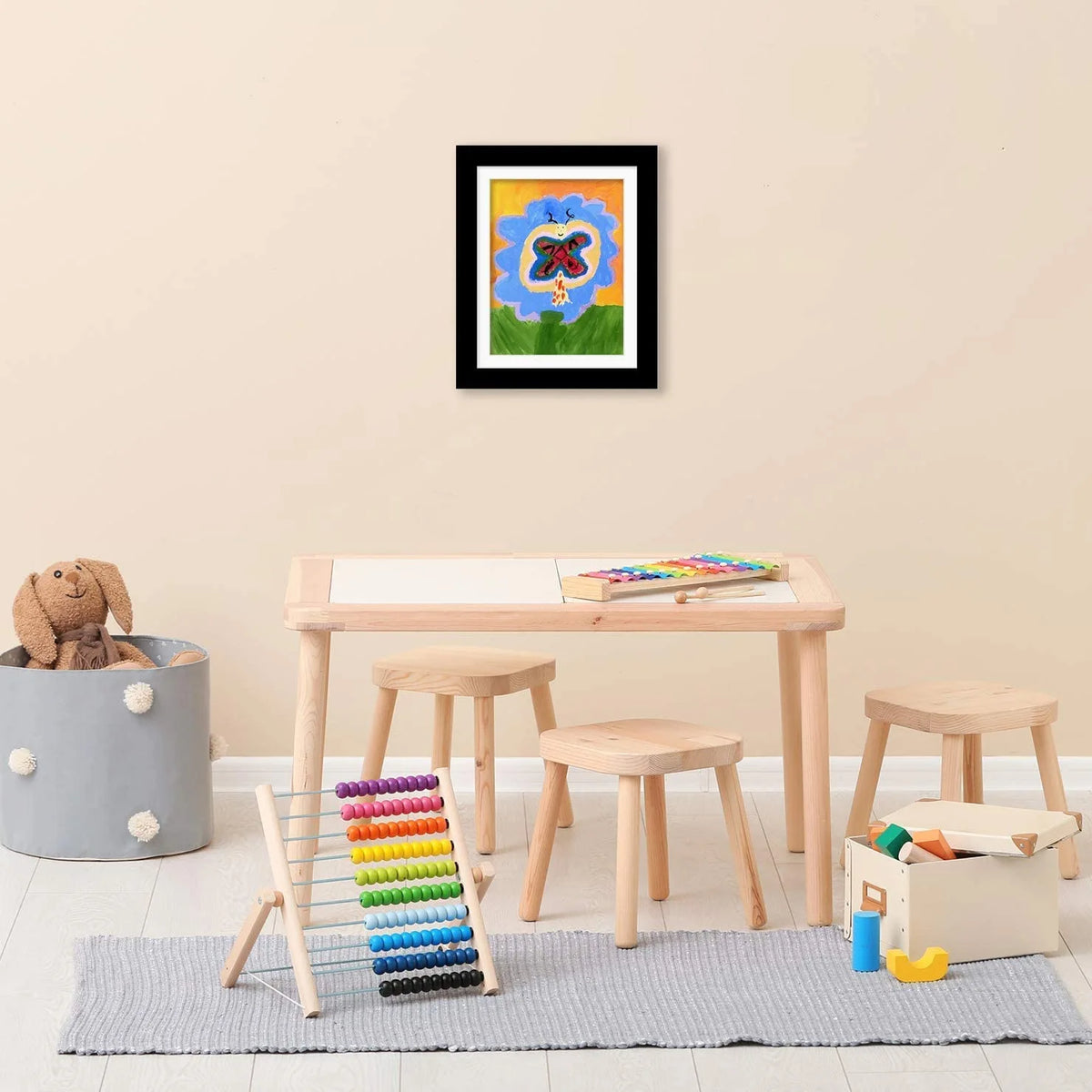 A framed artwork featuring a red butterfly on a blue background displayed on a wooden table.