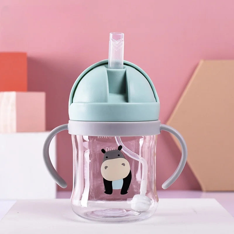 A clear glass straw cup with a light blue lid and handles is shown against a pink background.