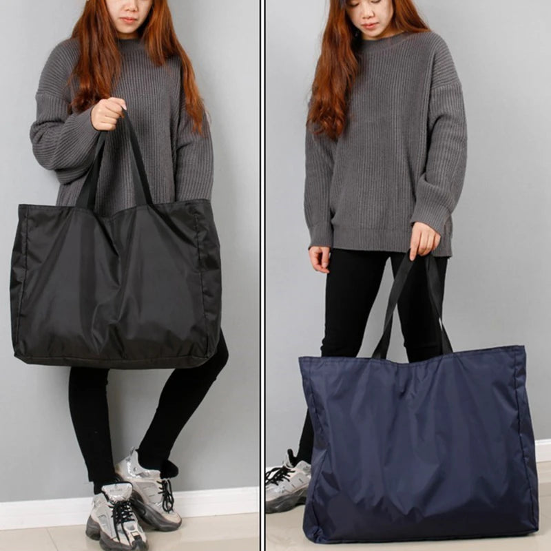 A young woman holds a dark blue reusable grocery tote bag against a gray background.