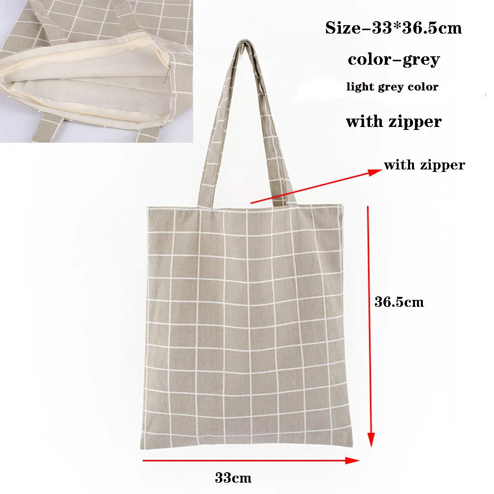 A light grey checkered canvas tote bag with a zipper, shown flat and standing.
