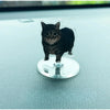 A black cat figurine is mounted on a clear acrylic base, designed as a dashboard ornament.
