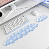 A set of translucent blue cloud-shaped ergonomic wrist rests for a keyboard and mouse are displayed on a white desk.