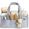 A gray floral diaper organizer bag filled with baby items including stuffed animals and grooming tools.