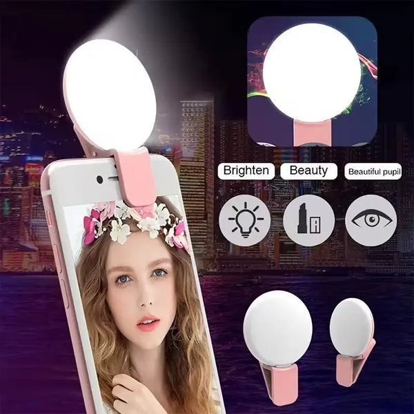 A woman is using a mini clip-on LED selfie ring light attached to her phone for a close-up portrait.
