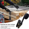 Close-up of heavy duty ratchet tie down straps being used to secure wooden planks on a flatbed.