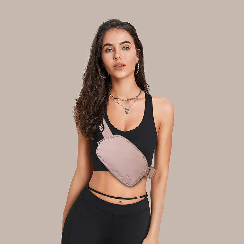 A woman models a pink adjustable nylon waist pack with a phone pocket worn over a black athletic top.
