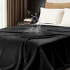 A black flannel blanket is draped over a bed, with white pillows visible in a bedroom setting.