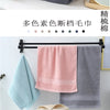 A set of six multi-colored cotton face towels hanging on a black rack.