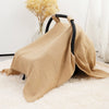 A beige breathable cotton muslin car seat and stroller cover draped over a black fabric frame on a white rug.
