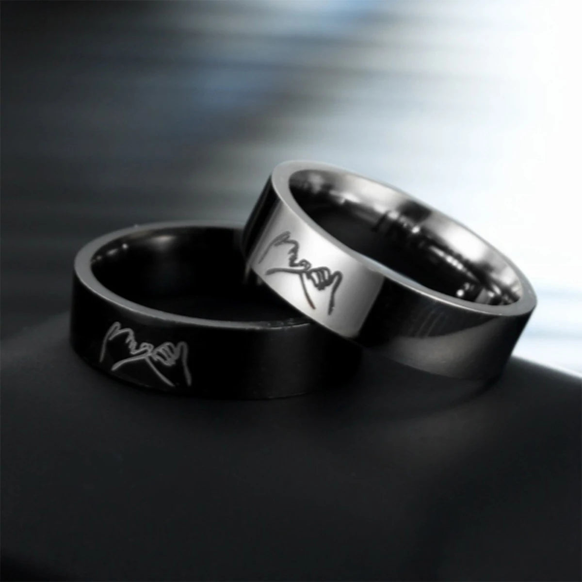 Ring et alliance en titane noir avec gravure 'Je t'aime', posés sur une surface sombre.