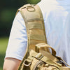 A close-up view of a tan crossbody chest bag with multiple zipper compartments and a MOLLE system worn on a person's torso.
