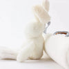 A white plush bunny toy with a rattle attached, shown in a close-up against a white background.