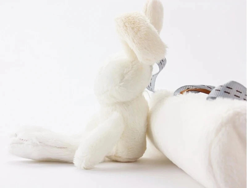 A white plush bunny toy with a rattle attached, shown in a close-up against a white background.