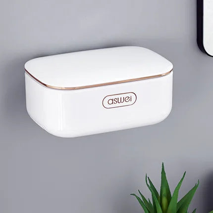 A white two-tier draining soap holder with a gold trim mounted on a gray wall.