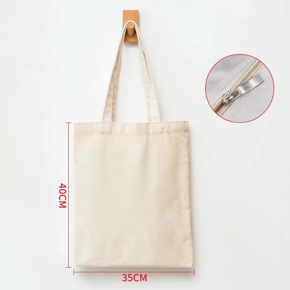 A beige canvas shopping tote bag with a wooden hanger and silver zipper detail.