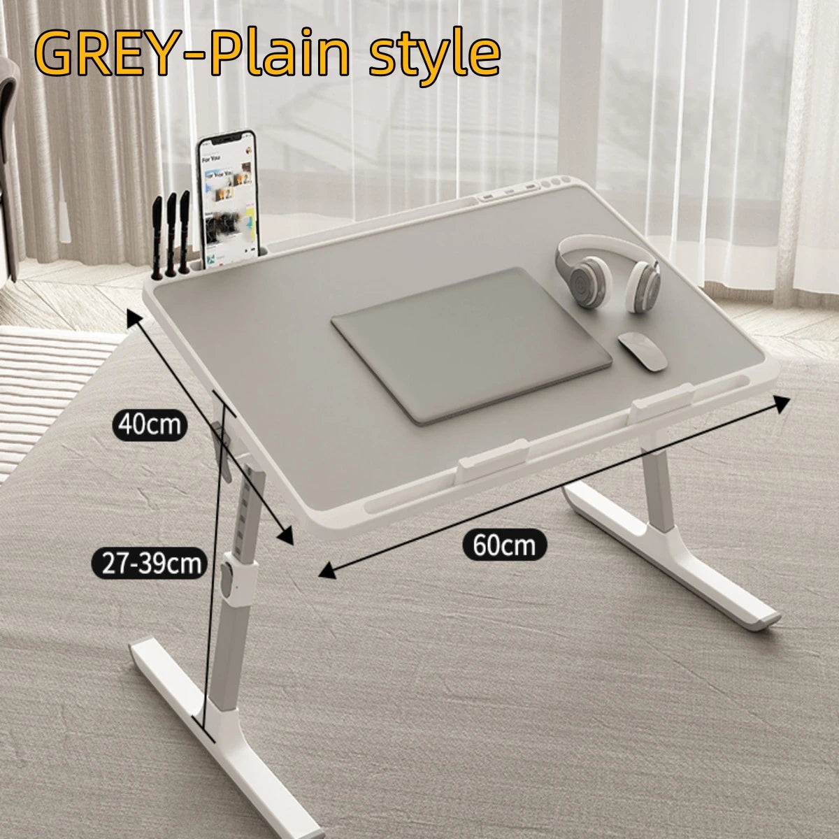 A grey plain style adjustable laptop bed tray with a storage drawer shown on a light wooden surface.