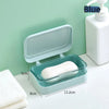 A light blue transparent soap dish with a drainage tray is shown next to a white pump bottle on a white surface.