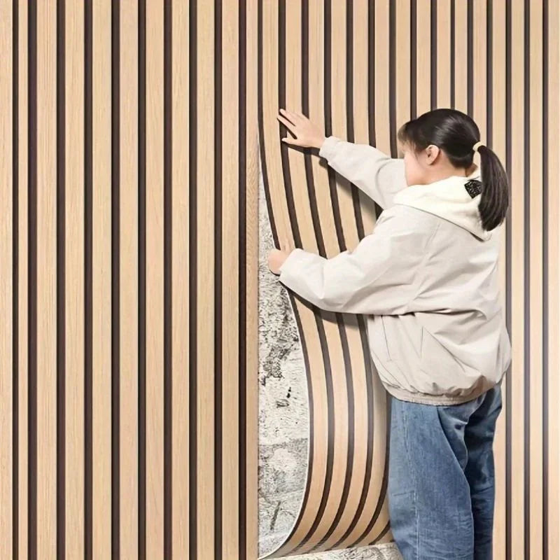 A person is touching a vertical wood grain wall panel, showcasing the texture and design of the self-adhesive wood panels.