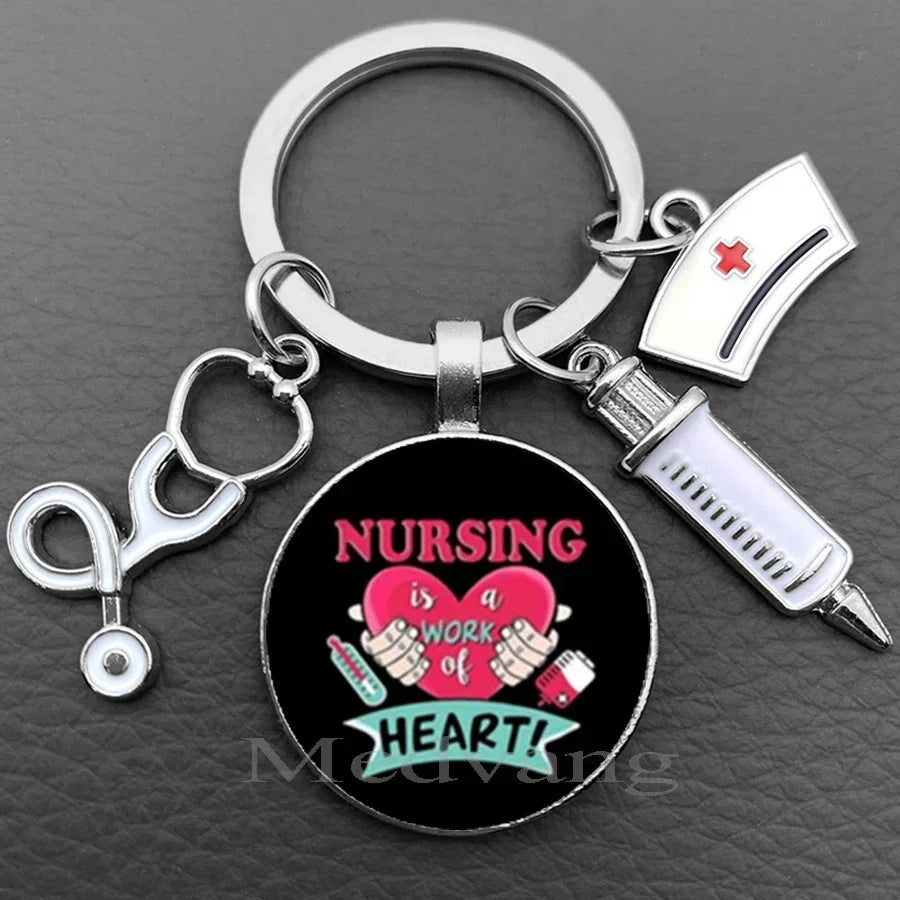 Silver keychain featuring a black disc with pink text that reads Nursing is a work of heart