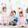 Two young children are posing with pink miniature cowboy hats on a white rug.