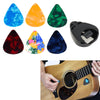 A set of colorful adhesive guitar pick holders and a black pick holder next to an acoustic guitar.