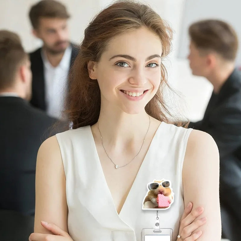 A smiling woman wearing a white top and necklace, with a cute hamster badge reel visible on her shirt.