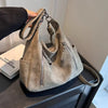 A beige matte leather crossbody hobo bag with adjustable strap resting on a dark surface.