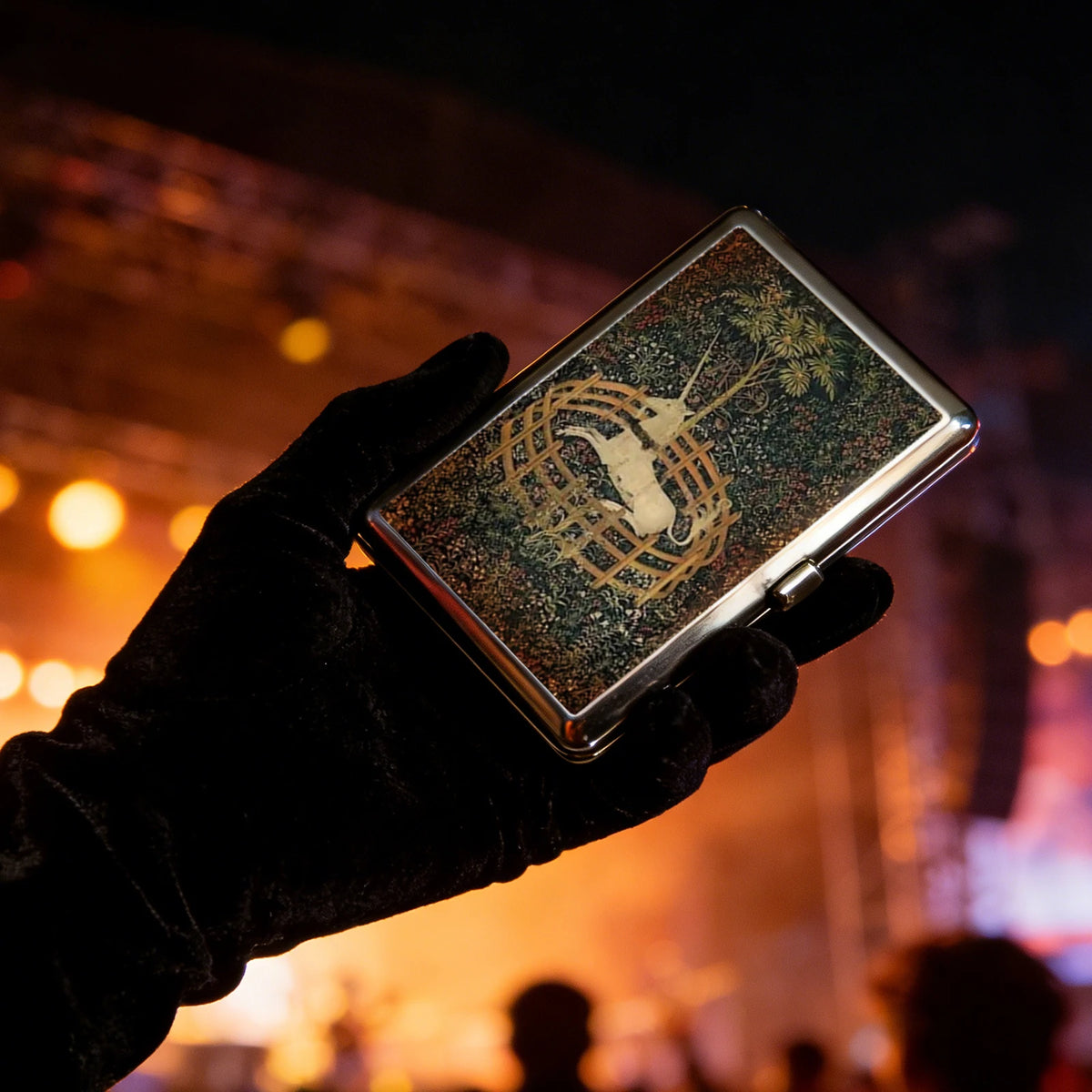 A hand holds a vintage metal card and cash case featuring an Art Deco design on a dark background.