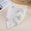 A white soft cotton baby bib with delicate gray and gold botanical embroidery, shown on a light background.