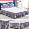 Monochrome three-layer gray elastic bed skirt with white pillows on a bed.