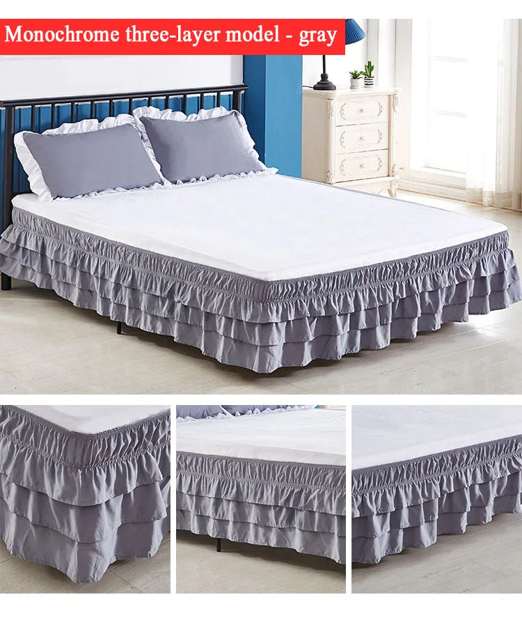 Monochrome three-layer gray elastic bed skirt with white pillows on a bed.